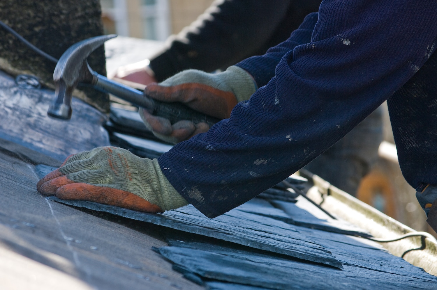 how long does it take to replace a roof close up handyman working with hammer and gloves to install new roofing