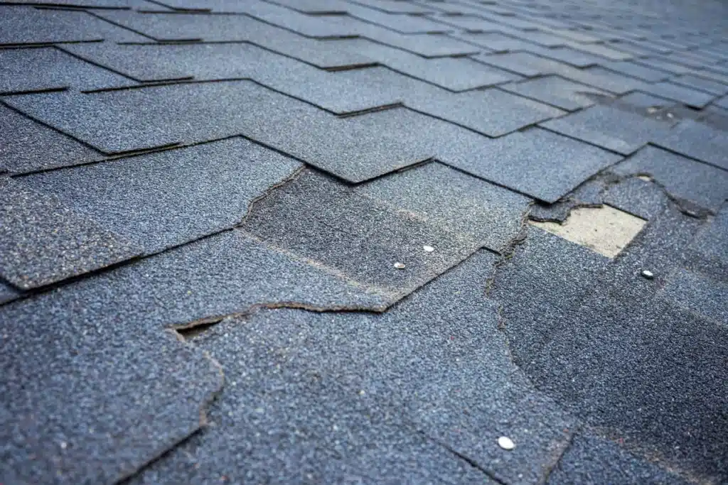 Granule loss on asphalt shingles revealing roof layers