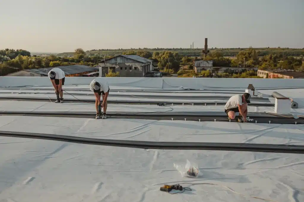 workers using powerful electric drill on flat roof protection
