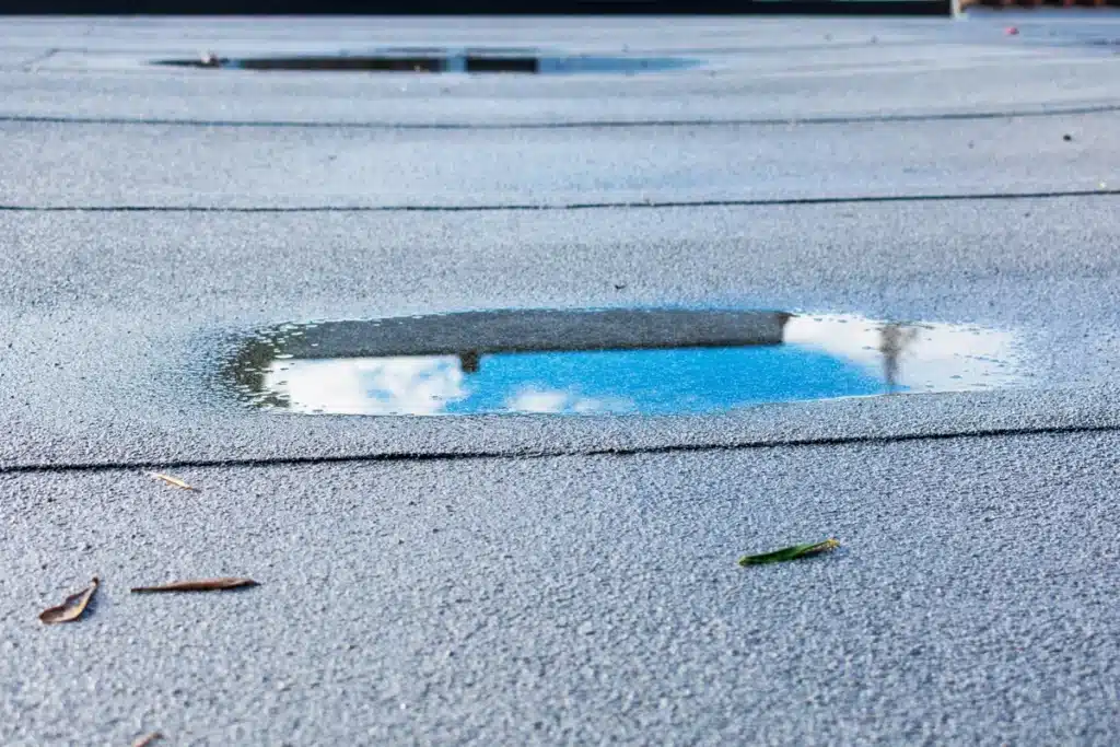 ponding rainwater on flat roof of house resulting drainage problems