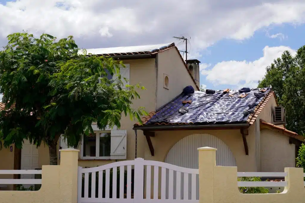 suburb house with damaged roof covered after storm