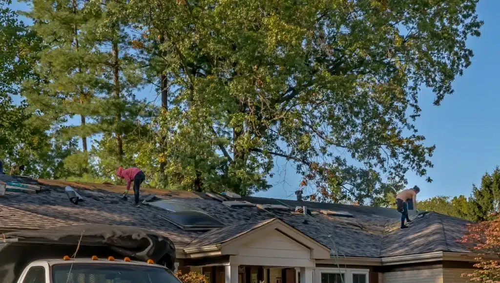 house roof with a tree behind getting replaced 