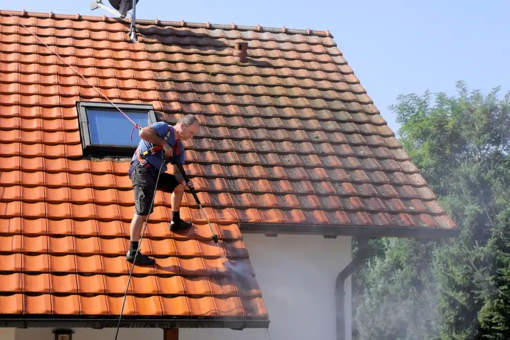 worker cleaning the roof with pressured water
