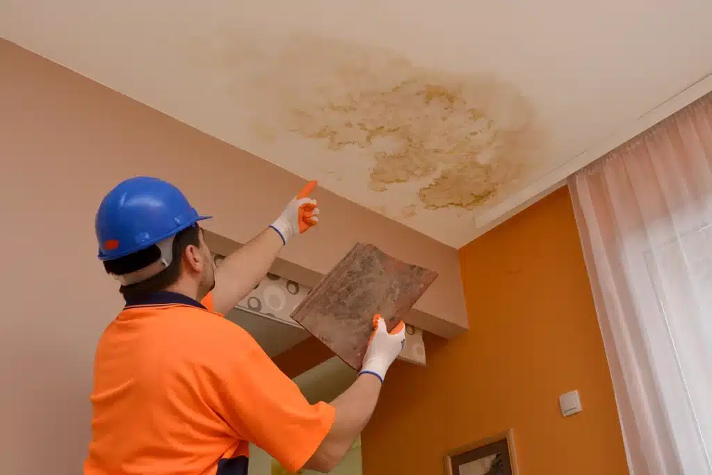 Roofer points at a water stain on the ceiling