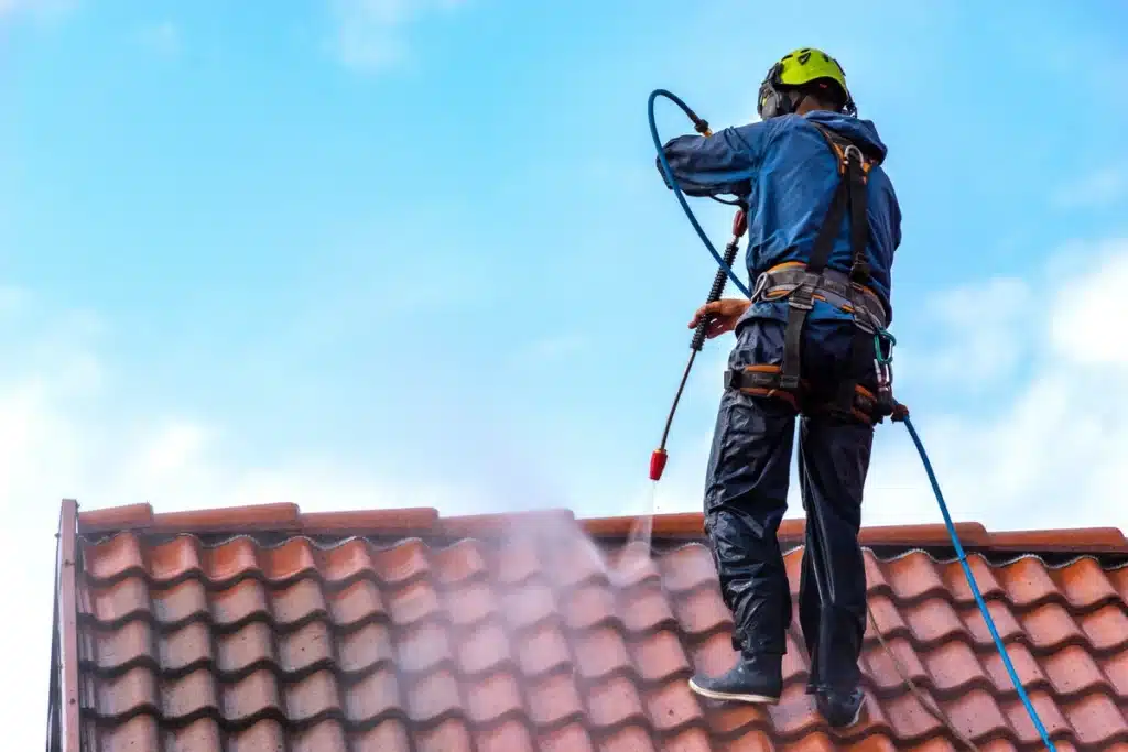 a roofer powerwashes a tile roof