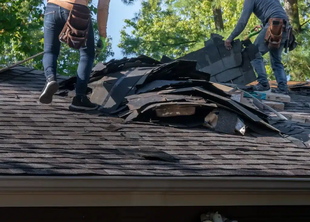 roofers pulling up asphalt shingles on a roof