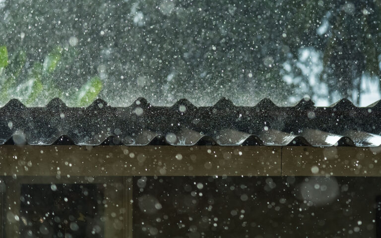 Side view of a roof with hail falling down on it