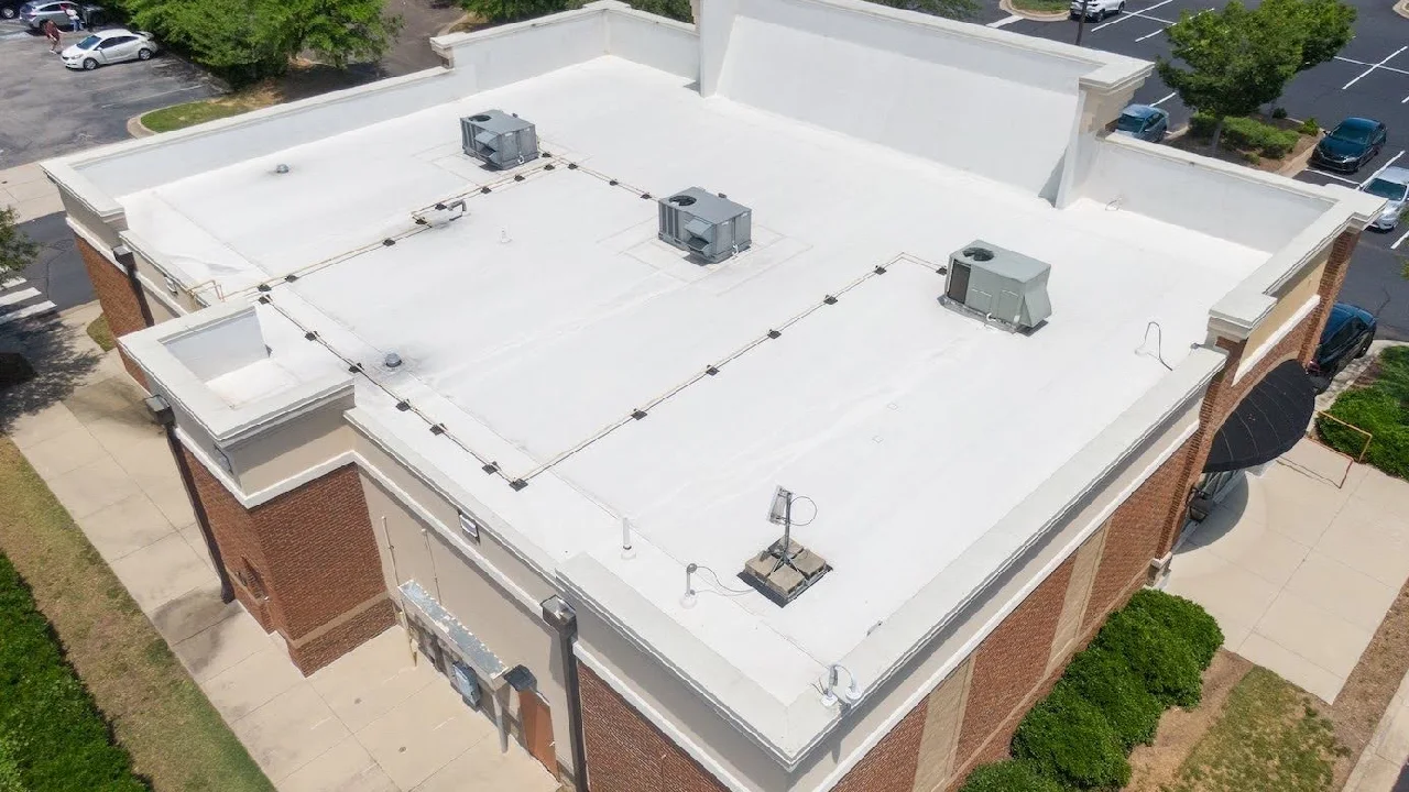 Aerial view of a completed white low-slope commercial roof on a brick building, Tectum Roofing Colorado