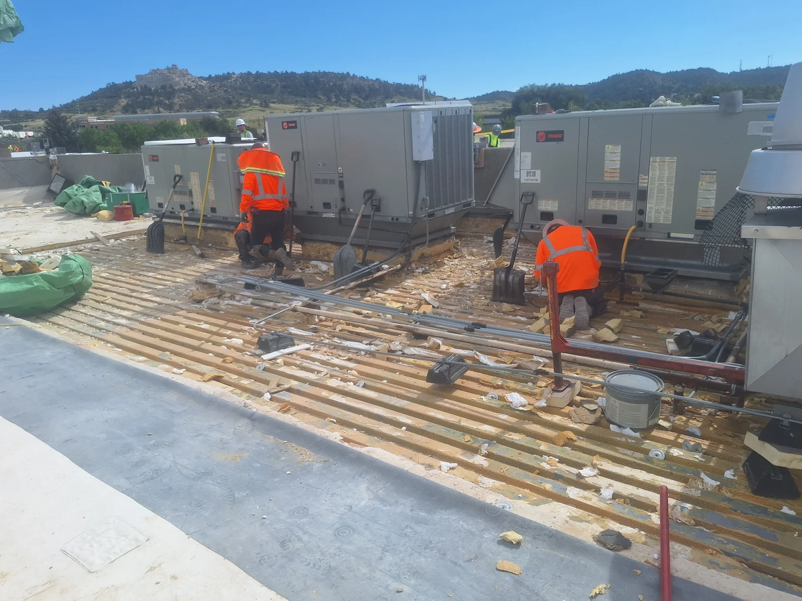 Roofing crew removing an existing commercial roof around rooftop mechanical units