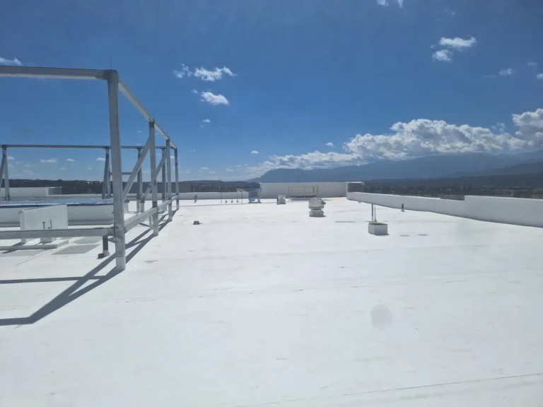 White commercial membrane roof with rooftop vents, support framing and mountains in the background