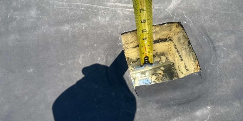 Close-up of a roof curb penetration on a commercial membrane roof with tape measure during a Tectum Roofing inspection