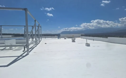 White commercial membrane roof with rooftop vents, support framing and mountains in the background